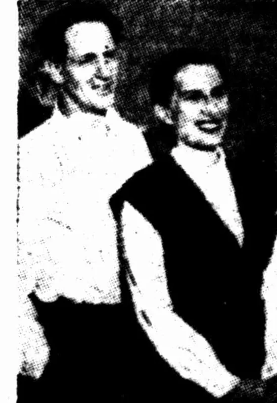 A newspaper photograph of a grinning man in an open-necked white shirt beside a smiling woman with short dark hair in a white blouse and dark waistcoat.
